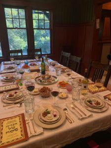 A large wooden table is set for a Passover seder.