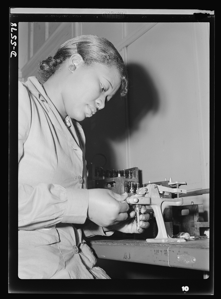 United States Office Of War Information, photographer by Rosener, Ann. Production. Aircraft engines. Reconditioning used spark plugs for reuse in testing airplane motors, Mighnon Gunn operates this small testing machine with speed and precision although she was new to the job two months ago. A former domestic worker, this young woman is now a willing and efficient war worker, one of many women who are relieving labor shortages in war industries throughout the country. Melrose Park, Buick plant. July, 1942. Image. Retrieved from the Library of Congress, .
